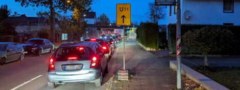 Ein auf einem Radweg aufgestelltes Umleitungszeichen neben einem Laternenmasten, die den Rad-/Gehweg einengen.