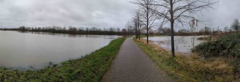 Ein asphaltierter Weg zwischen zwei Wasserflächen.