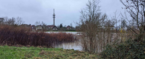 Ein Postturm vor einer Wasserfläche.