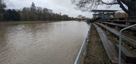 Im Bild rechts eine Tribüne aus Holzbohlen mit einem Stahlgeländer links. Die Veranstaltungsföäche links ist komplett überflutet.