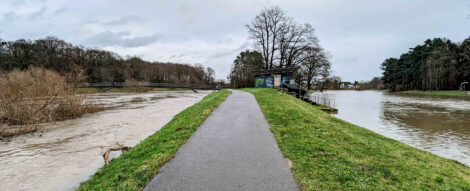 Ein asphaltierter Weg zwischen zwei Wasserflächen.