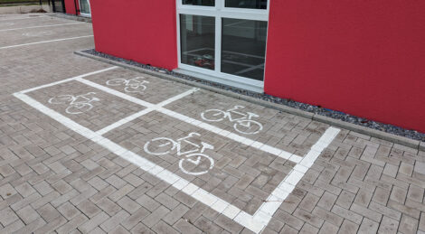 Vier kleine mit weißer Farbe markierte Rechtecke mit jeweils einem Fahrradpiktogramm sollen entsprechende Parkflächen darstellen.