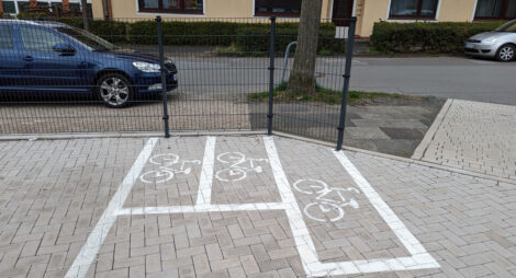 Drei kleine mit weißer Farbe markierte Rechtecke mit jeweils einem Fahrradpiktogramm sollen entsprechende Parkflächen darstellen.