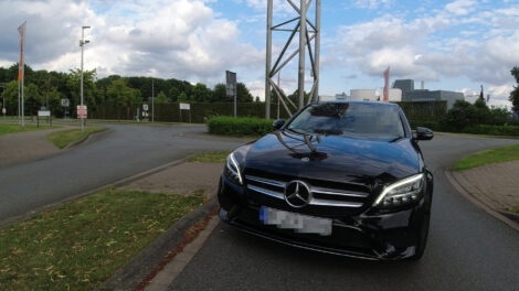 Ein dunkler Mercedes möchte aus der verkehrten Richtung kommend auf die falsche Spur aus einem Kreisel ausfahren und steht mit seiner Front im Gegenverkehr.
