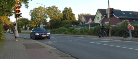 Ein Fahrzeug ist mit den Vorderrädern wenige Zentimeter über der Haltelinie einer ampelgesteuerten Querung für den Fußverkehr zu sehen. Die Ampel zeigt für das Fahrzeug rot an.