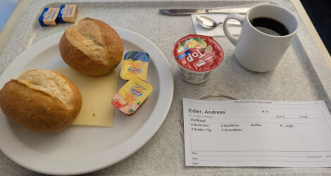 Zwei Brötchen, Marmelade, Käse, Kaffee und Yoghurt auf einem Tablett in einem Krankenhaus.