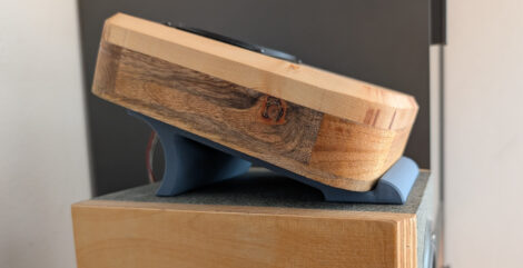 Seitenansicht eines kleinen Lautsprechers, der mit der Rückwand auf der Oberseite eines großen Standlautsprechers liegt. Damit ein ca. 20° Winkel entsteht, liegt der Lautsprecher auf einer Rampe mit einer Abstützung am hinteren Ende..