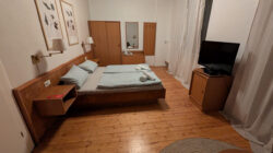 Ein Hotelzimmer mit Doppelbett in einer '70er Jahre Anmutung mit schönem Holzfußboden.