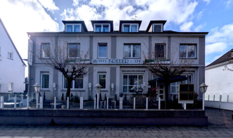 Frontansicht des "Hotel Breuer". Die Fensterfront hat jweils 6 Fenster auf 2 Etagen und im Dach noch jeweils 4 kleine Gauben.