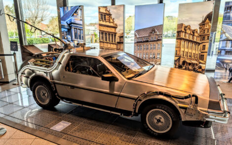 Der DeLorean aus "Zurück in die Zukunft" steht auf einem sehr flachen Podest der Lobby einer großen Halle.