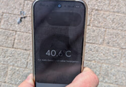Das Thermometer eines Google Pixel 9 pro wird ca. 30 Zentimeter über die von der Sonne beschienenen Pflastersteine eines Weges gehalten und zeigt 40,5°C an.