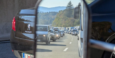 Stau auf einer ansteigenden Autobahn. Das Bild ist im Zusatzrückspiegel für Wohnwagen aufgenommen.