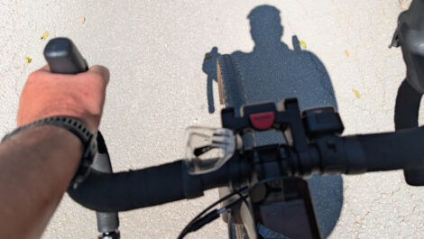 Der Rennradlenker eine Gravelbikes mit der linken Hand des Fahrers am Lenker. Auf der Straße sieht man den Schatten des Oberkörpers und des Kopfes vom Fahrer.