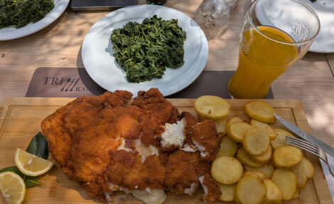 Ein riesiges Cordon-Bleu mit Bratkartoffeln und Spinat auf einem extra Teller