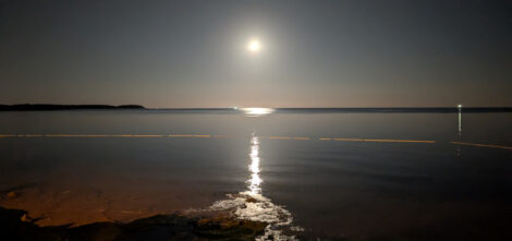 Der Mond steht niedrig über dem Meer und spiegelt sich in leichter Dünung.