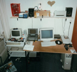 Der Schreibtisch in einem "Computerzimmer" Ende der '90er Jahre. Ein riesiger Laptop, DOS-Rechner und ein modernerer PC bilden ein Ensemble.
