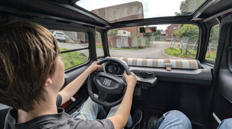 Blick nach vorne aus einem Fiat Topolino. Am Steuer sitzt ein sehr junger Junge, der das Fahrzeug nur auf privatem Grund fahren darf!